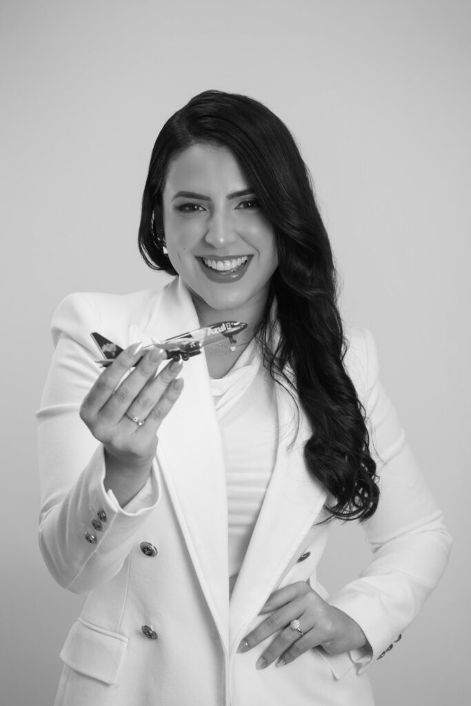 Foto em preto e branco da advogada Andreza Lima segurando um avião em miniatura