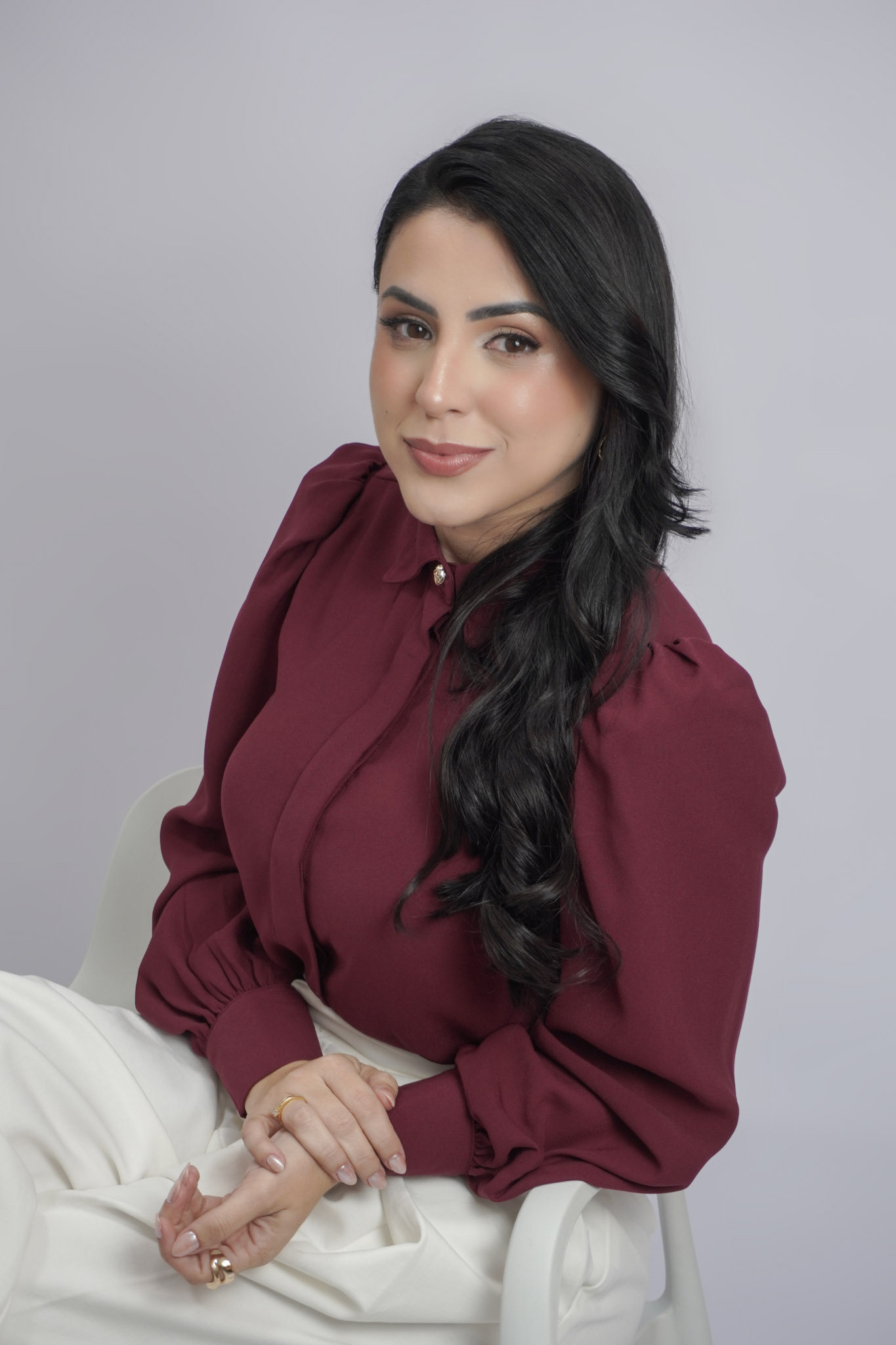 Ensaio corporativo para advogada: Andreza Lima de blusa vinho sentada no Estúdio Hamo