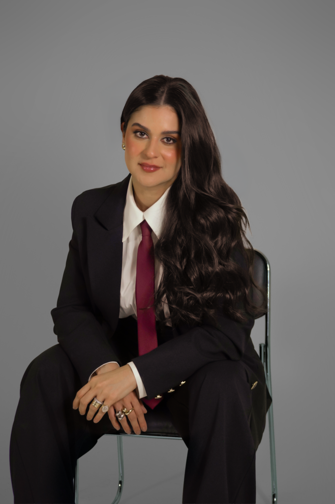 Dra. Wilma Viviane, médica capilar, em foto corporativa sentada com terno preto e gravata vinho