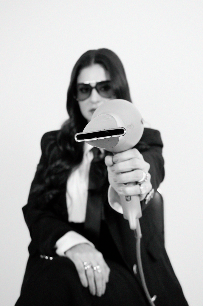 Foto corporativa em preto e branco da Dra. Wilma Viviane segurando um secador de cabelo